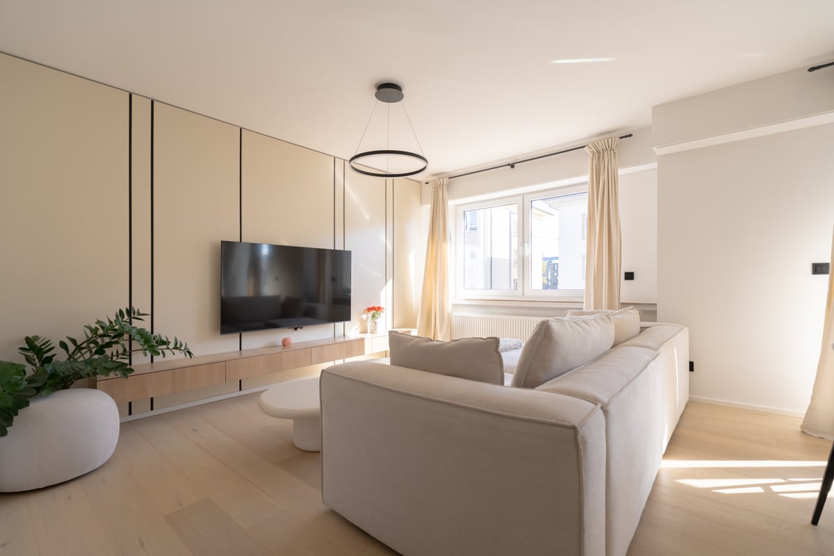 Salon meublé avec canapé, meuble TV et grandes fenêtres